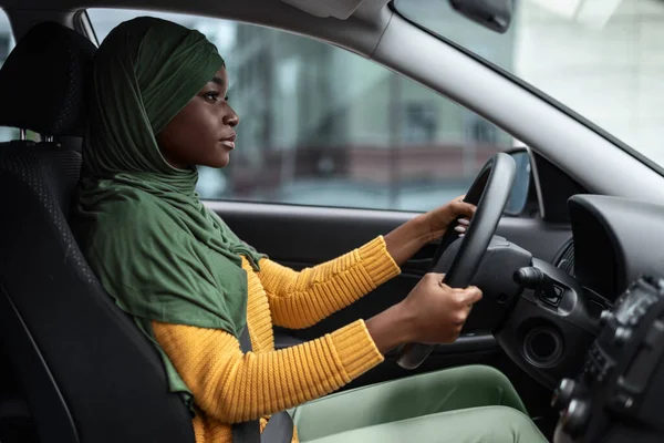 Jonge bestuurder. Serieuze zwarte moslim dame rijden auto gericht op de weg — Stockfoto
