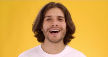 Genç mutlu beyaz adam kameraya gülüyor, heyecanlı ve mutlu hissediyor, yakın portre