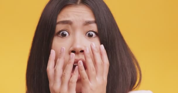 Primer plano retrato de joven miedo asiático dama, sensación miedo y pánico, naranja estudio fondo — Vídeo de stock