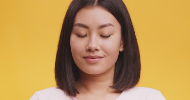 Primer plano retrato de youn positivo asiático dama asintiendo cabeza de acuerdo, expresando aceptación, naranja fondo — Vídeos de Stock