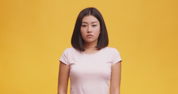 Ung ledsen asiatisk kvinna andas djupt och pipa läppar, känsla upprörd, orange studio bakgrund — Stockvideo