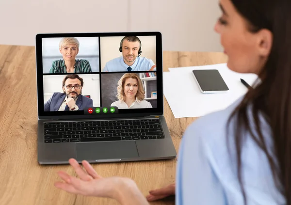 Бізнес-леді розмовляє з колегами роблячи відео дзвінок на комп'ютері в приміщенні — стокове фото