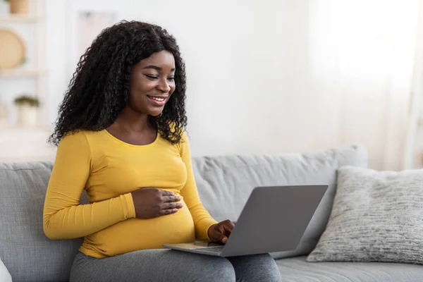 Усміхнена чорна вагітна леді використовує ноутбук вдома — стокове фото