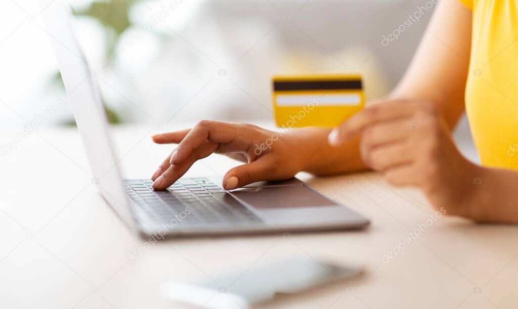 Black lady using laptop and debit credit card at home