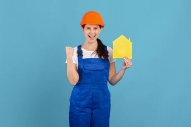 Sert Şapkalı Aşırı Neşeli Kadın ve Sarı Kağıt Ev Figürü Tutan Kapaklı Kadın