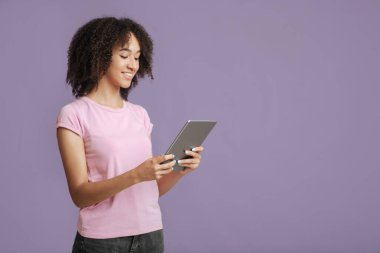 Modern cihazlarla çalışmak ve rahatlamak. İnternette pembe tişörtlü, gülümseyen kadın sörf yapıyor.