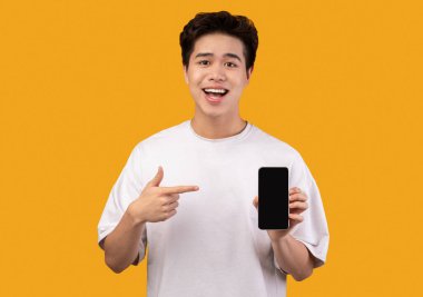 Asyalı adam boş akıllı telefon ekranı gösteriyor ve işaret ediyor.
