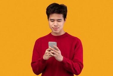 Stüdyoda cep telefonu kullanan gülümseyen Asyalı genç adam.