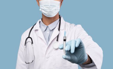 Tanınmayan erkek doktor elinde virüs aşısıyla şırınga tutuyor.