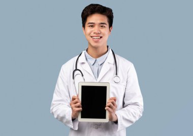 Asyalı doktor elinde boş ekranlı tablet tutuyor.