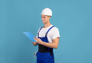 Tulum giymiş gülümseyen erkek tamirci ve not defterine not yazıyor.