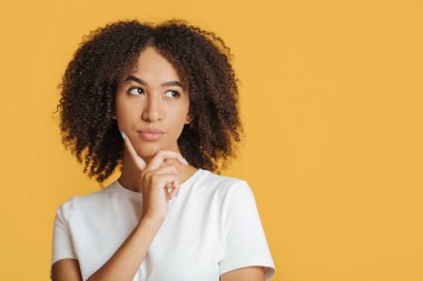 Zor seçim, teklif ya da karar vermek. Düşünceli genç Afrikalı Amerikalı kadın parmağını çenesine bastırıyor.