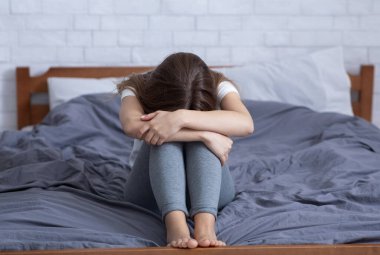 Stresli genç kadın negatif duygular içinde, depresyonda ve yatakta ağlıyor.