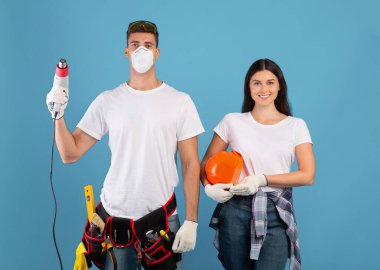 Ev tamiri. İnşaat Aletleri Mavi Arkaplanda Poz Veren Genç Çift