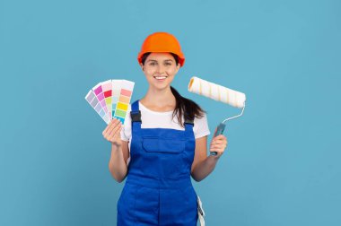 Üstü örtülü genç kadın renk paleti ve paten fırçasıyla poz veriyor.