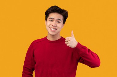Mutlu Asyalı adam başparmağını kaldırıyor ve gülümsüyor.