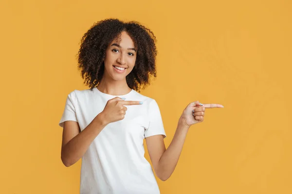 Reclame en presentatie concept. glimlachende Afrikaans-Amerikaanse dame wijzend met vingers naar lege ruimte — Stockfoto