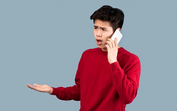 Confuso asiatico uomo parlando su smartphone a studio — Foto Stock