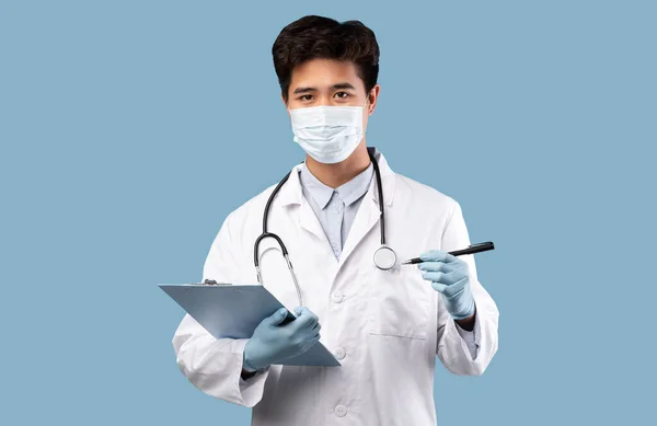 Ασιάτης γιατρός με ιατρική μάσκα κρατώντας φάκελο και πένα — Φωτογραφία Αρχείου