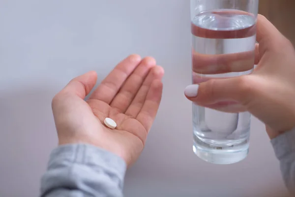 Vista de cerca de una mujer joven con un vaso de agua que toma antidepresivos o pastillas para dormir — Foto de Stock