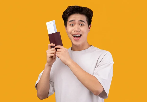 Podekscytowany młody Azjata posiadający bilety i paszport — Zdjęcie stockowe