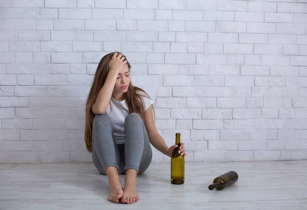 Mujer milenaria sintiéndose deprimida, bebiendo alcohol para aliviar el dolor emocional en el suelo en casa, espacio para copiar — Foto de Stock