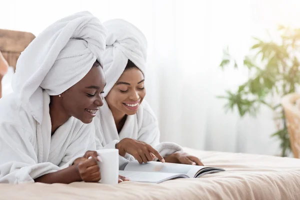 Gelukkig afrikaanse amerikaanse vriendinnen in badjassen rusten thuis — Stockfoto