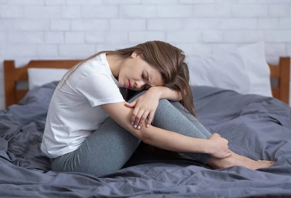 Depressive junge Frau sitzt allein in ihrem Bett, leidet unter Einsamkeit oder Schlaflosigkeit und fühlt sich unglücklich — Stockfoto