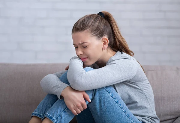 Millennial signora con depressione seduta sul divano a casa, chiudendo gli occhi, avendo esaurimento nervoso o attacco di panico — Foto Stock