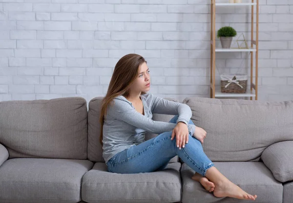 Самотня молода леді сидить на дивані вдома, відчуває депресію і розчарування, страждає від емоційного виснаження — стокове фото