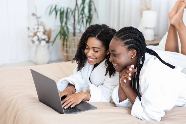 Vackra svarta flickvänner läser skönhet blogg, ligger på sängen — Stockfoto