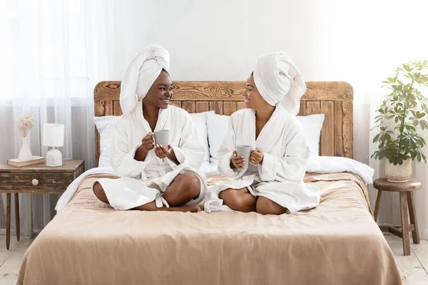 Young black girlfriends drinking tea in bedroom — 图库照片