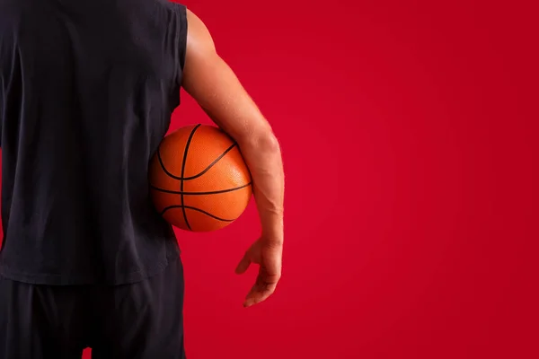Fechar-se de jogador de basquete millennial segurando bola sobre fundo estúdio vermelho, espaço para texto — Fotografia de Stock