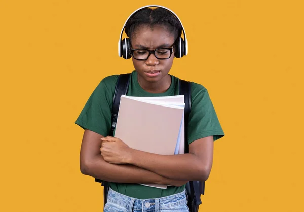 Unhappy Victimized African Girl Holding Copybooks Standing Over Yellow Background