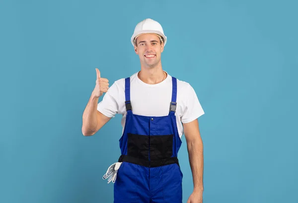 Retrato de joven trabajador de mantenimiento en Hardhat y cubiertas que muestran el pulgar hacia arriba —  Fotos de Stock