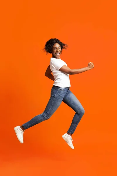 Ativo senhora negra correndo sobre fundo laranja — Fotografia de Stock