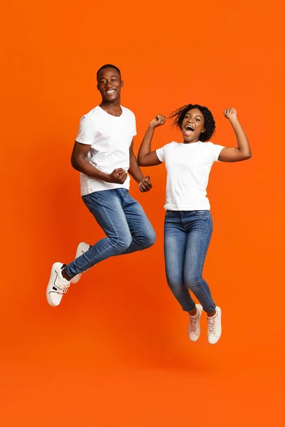 Alegre casal afro-americano apertando punhos e pulando — Fotografia de Stock