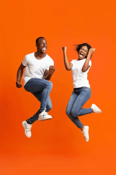 Emocional Africano americano casal vencedores apertando punhos e pulando — Fotografia de Stock