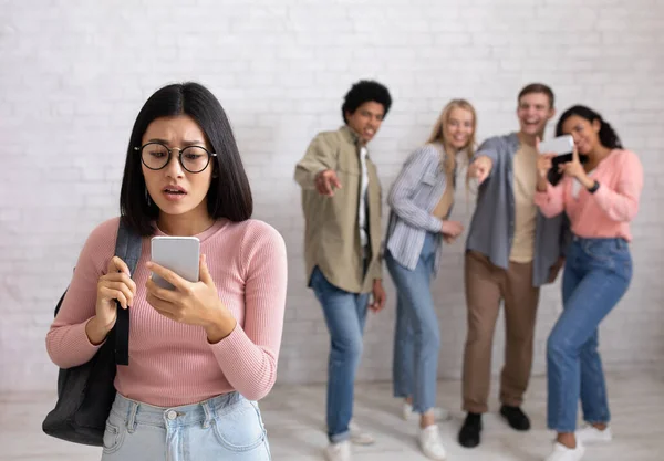 Humillación, educación e intimidación. Triste asiático joven hembra en gafas mira en el teléfono — Foto de Stock