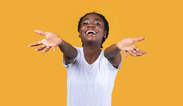 Excited Black Woman Stretching Hands To Camera Over Yellow Background