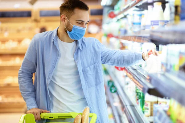 Ο άνθρωπος στην ιατρική μάσκα ψώνια στο σούπερ μάρκετ λαμβάνοντας γάλα — Φωτογραφία Αρχείου