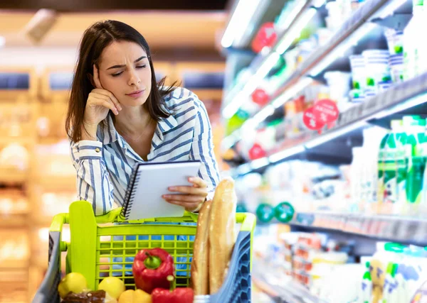 Young woman with shopping list in supermarket — Stock Photo, Image