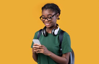 Sarı Arkaplanda Duran Akıllı Telefonu Kullanan Mutlu Afrikalı Kız Öğrenci