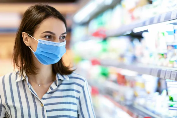 Jonge vrouw in het gezicht masker winkelen in supermarkt tijdens quarantaine — Stockfoto