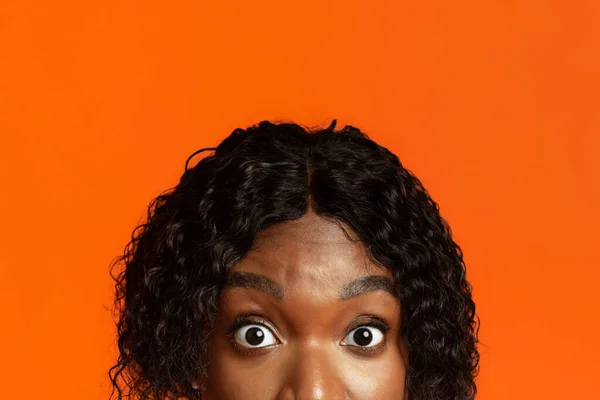 Fechar-se de mulher negra olhos surpresos, fundo laranja — Fotografia de Stock