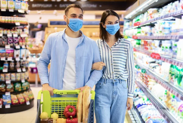 슈퍼마켓에서 방호복을 입고 쇼핑하는 젊은 부부 — 스톡 사진