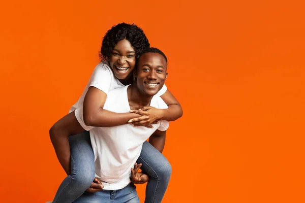 Felizes amantes negros posando no fundo do estúdio laranja — Fotografia de Stock