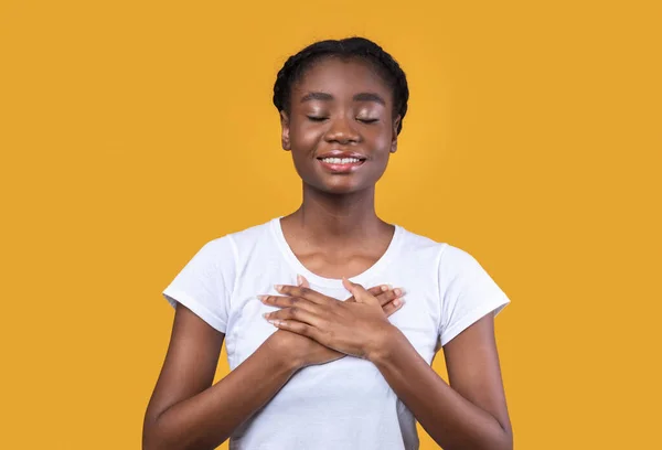 黄色の背景に胸に手を押して感謝アフリカの女性 — ストック写真