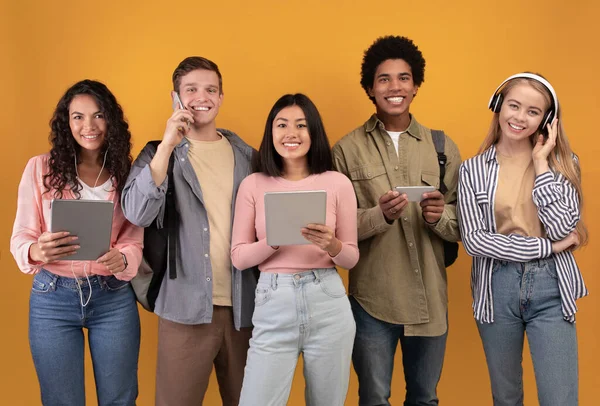 Appareils modernes, mode de vie et étudiants à l'étranger. Jeunes gens multiraciaux souriants avec des appareils modernes — Photo