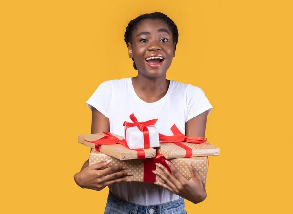 Opgewonden zwarte vrouw vasthouden verpakt geschenken poseren over gele achtergrond — Stockfoto
